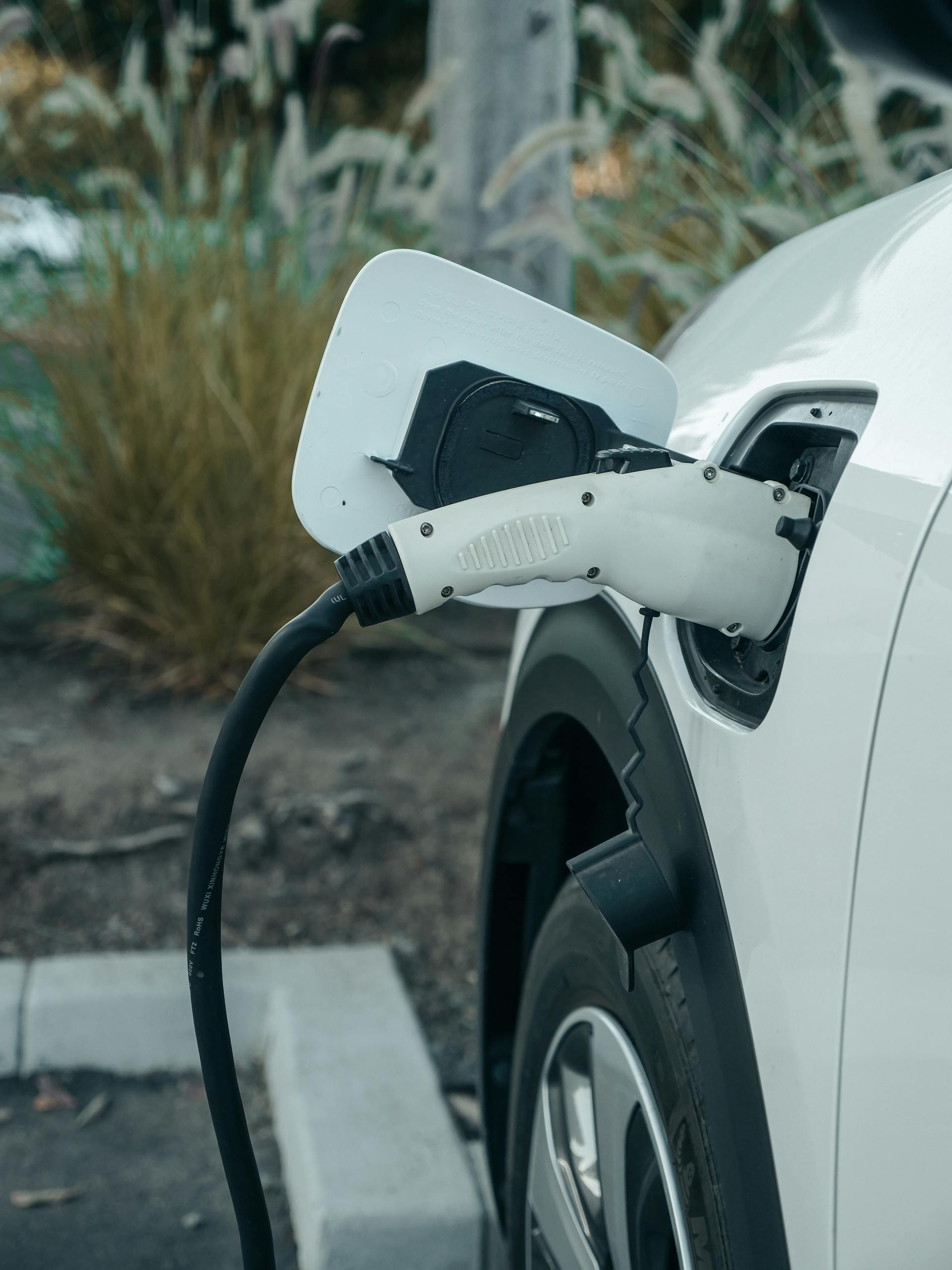 Close-up of electric vehicle connected to charging station outdoors.